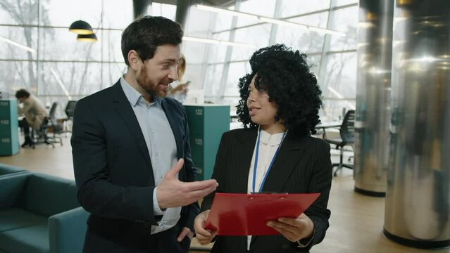 Young colleagues discussing new project before the conference. Close-up shot of professionals revising documents and reports. High quality 4k footage