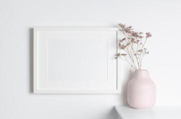 White picture frame mockup on wall with botanical decorations