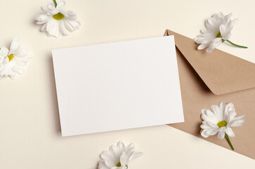 Invntation or greeting card mockup with envelope and flowers, flat lay with copy space