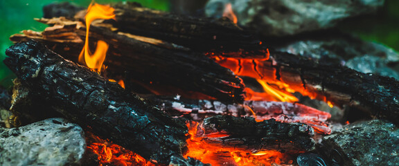 Vivid smoldered firewoods burned in fire close-up. Atmospheric warm background with orange flame of campfire. Unimaginable full frame image of bonfire. Burning logs in beautiful fire. Wonderful flame.
