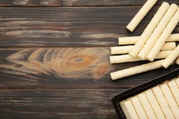 Delicious milk wafer rolls on brown background