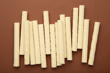 Delicious milk wafer rolls on brown background