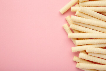 Delicious milk wafer rolls on pink background