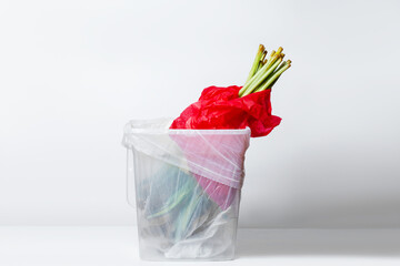 wilted flower. Wilted tulips in red packaging. In the garbage bucket. Inverted down