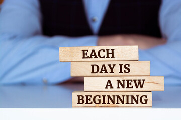 Wooden blocks with words 'Each day is a new beginning'.