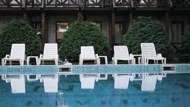 Lounger with sun hat and swimming pool in luxury resort