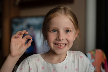 The little girl has just pulled her baby tooth and is waiting for the tooth fairy. A child shows...