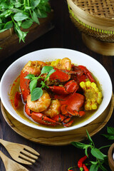 Kepiting Saos Padang or Indonesian Spicy crabs, served with shrimp and corn. Selective focus on dark wooden background.