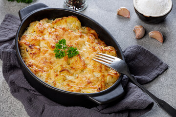 Potato casserole with cheese and parsley on stone background. French cuisine, top view