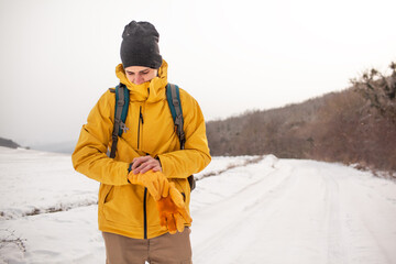 Fototapeta na wymiar The man dresssed yellow warm jacket and trousers, bagpack traveling in the snow landscape