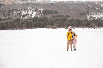 Happy family have fun with one-year-old baby in the snow, people dresed warm clothes iand walking in the winter vacations