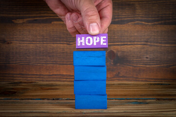 HOPE concept. Colorful blocks on a wooden texture background
