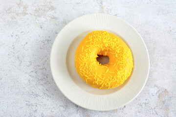 yellow donut with mango taste isolated on white saucer isolated, topview