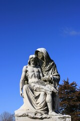 Fototapeta na wymiar Statue of the Virgin Mary holding Jesus against a blue sky.