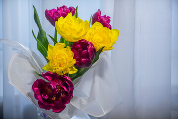 Bouquet of flowers with yellow and red tulips against the window.