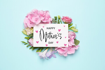 Happy Mother's Day greeting card and beautiful flowers on pale light blue background, flat lay
