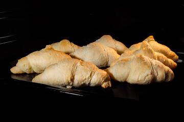Eight croissants baking and rising on tray in electric oven. French cuisine, homemade bakery, breakfast, food, cooking and pastry concept