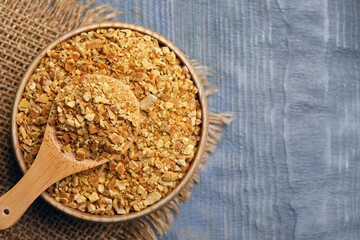 Bowl and spoon with dried orange zest seasoning on grey wooden table, top view. Space for text