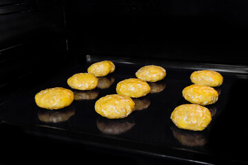 Nine uncooked homemade oatmeal cookies in row on metal sheet in oven, black background. Dessert, cookery, baking, gastronomy, food and raw concept