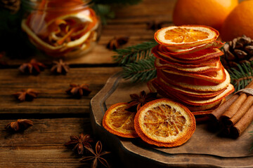 Dry orange slices, anise stars and cinnamon sticks on wooden table, space for text