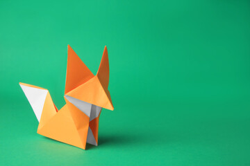 Origami art. Handmade orange paper fox on green background, space for text