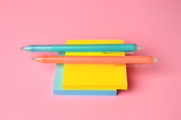 Colorful paper notes with erasable pens on pink background, closeup