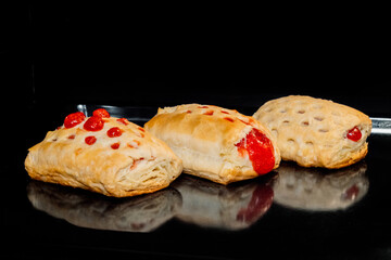 Three baked puff pastry buns with red strawberry jam on tray in electric oven, black background. Homemade bakery, food, cooking and pastry concept