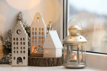 Beautiful house shaped candle holders and Christmas decor on windowsill indoors. Bokeh effect