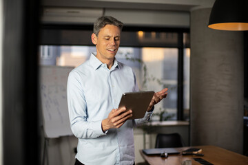 Fototapeta premium Portrait of businessman in office. Man using digital tablet. Businessman having video call.