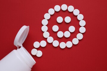 Happy emoticon made of antidepressants on red background, flat lay