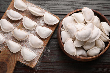 Raw dumplings (varenyky) on brown wooden table, flat lay
