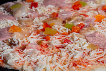 Uncooked pizza with with ham, mushroom, pepper, cheese in electric oven - close up view, macro. Italian cuisine, homemade bakery, fast food, semi-finished products and raw concept