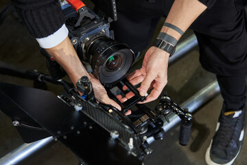 Fototapeta na wymiar male hands of a cameraman adjust the body kit of a professional movie camera before filming