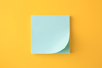 Blank paper note on orange background, top view