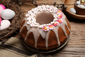 Delicious Easter cake decorated with sprinkles near different eggs on wooden table, closeup