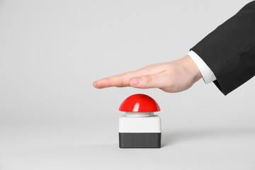 Man pressing red button of nuclear weapon on light gray background, closeup with space for text....