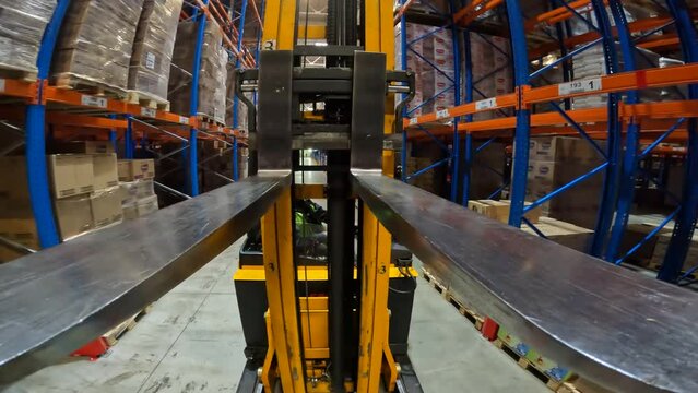 Modern forklift works in a warehouse. The work of a forklift in a warehouse pov. Work of special equipment in the warehouse, pov