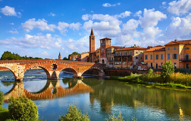 Panoramic view to Bridge Ponte Pietra in Verona on Adige river, Veneto region, Italy. Sunny summer day panorama and blue dramatic sky with clouds. Ancient european italian terracotta color houses