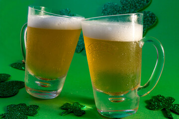 Two mugs of cold beer on green background with shamrock and hat, close up, st patrick's day