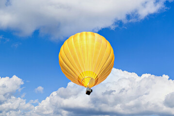 Colorful hot air balloon flying over blue sky with white clouds