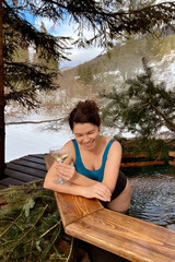woman with glass of white wine in outdoor hot tub in the mountains for spa and relaxation in...