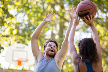 group of happy teenagers playing basketball outdoors