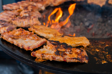 Barbecue, outdoor cooking, gastronomy, cookery, street food concept. Process of cooking fresh juicy meat steaks on brazier at summer local food market - close up view