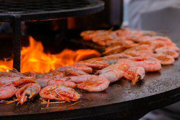 Process of grilling fresh red king prawns on brazier with hot flame at summer local food market - close up view. Outdoor cooking, gastronomy, seafood, barbecue, street food concept