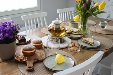 Afternoon tea with Delicious Food and Drink Selections, Including a Beautiful Glass Teapot of Fresh Flowers and Flavorful Tea