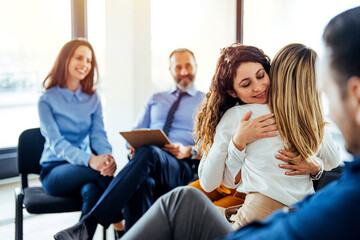 Support group gathering for a meeting. Young woman discussing with people at entrance hall. Males and females are sharing ideas during group therapy. 