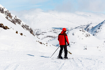 Defying the slope: an unrecognizable person with his back turned in red clothes skiing on the mountain. winter sports. 