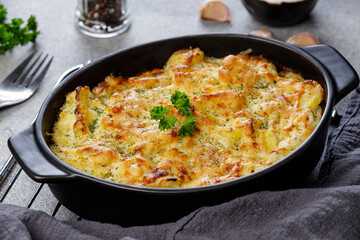 Obraz na płótnie Canvas Potato casserole with cheese and parsley on stone background. French cuisine.