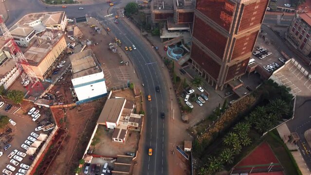 Drone shot rotating above traffic on road N2 in downtown Yaounde, sunny Cameroon