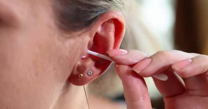 Closeup of woman cleaning ears and using Q-tip